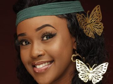 Azziad Nasenya in green outfit with gold butterfly earrings and hair accessory, studio portrait