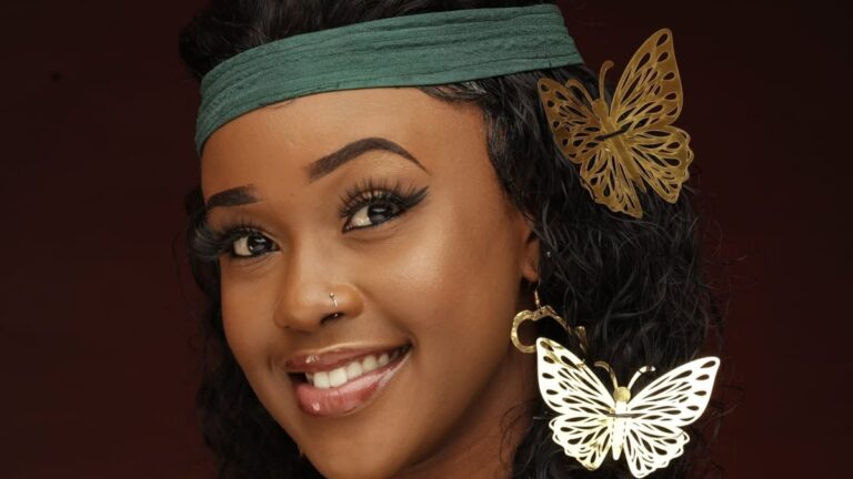 Azziad Nasenya in green outfit with gold butterfly earrings and hair accessory, studio portrait
